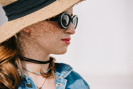 portrait of beautiful young woman in hat and sunglasses looking awayの写真素材