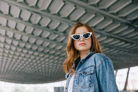 portrait of young fashionable woman in denim clothing and retro sunglassesの写真素材