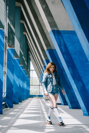 fashionable young woman in denim clothing and high socks roller skating aloneの写真素材