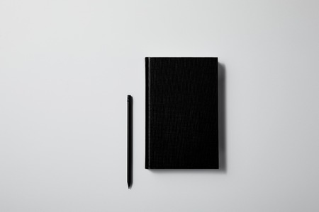 top view of black notebook with pencil on white surface for mockupの写真素材