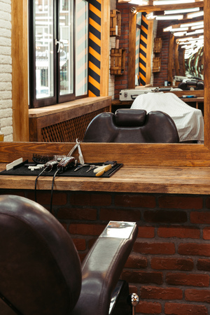modern barbershop interior reflected in mirror and professional barber tools on wooden shelfの写真素材