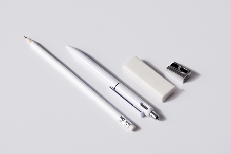 close-up shot of pen with pencil, eraser and sharpener in row on white surface for mockupの写真素材