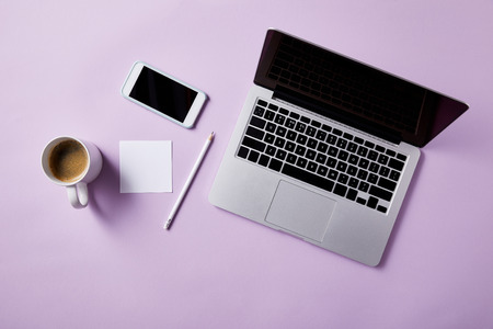 top view of workplace with coffee and devices on pink tabletop for mockupの写真素材