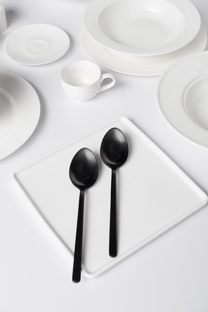 selective focus of various plates, two spoons and cup on white tableの写真素材