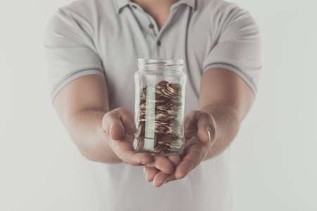cropped image of man showing jar of coins in hands isolated on white, saving conceptの写真素材