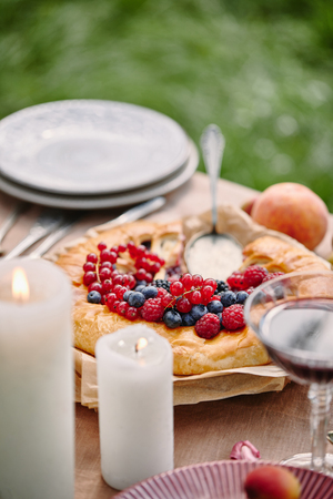 pie with berries, candles on table in gardenの写真素材