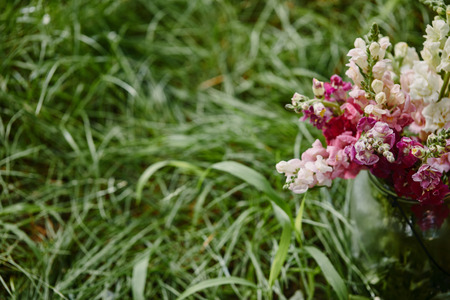 bouquet of pink and white flowers in glass jar on green grass