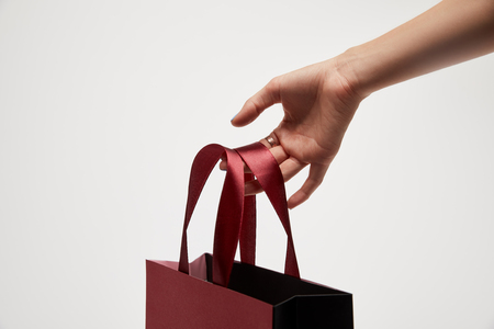 cropped image of woman holding red shopping bag in hand isolated on whiteの写真素材