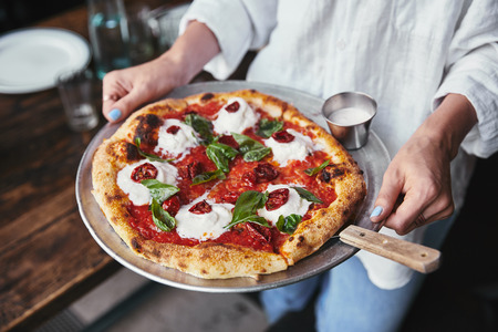 cropped shot of woman carrying plate with delicious pizzaの写真素材
