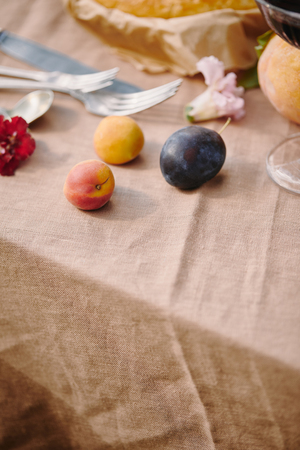 plums and utensils on beige tablecloth in gardenの写真素材