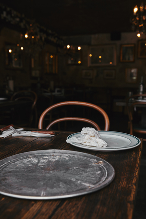 empty metal kitchen tray with white plate on wooden table at restaurantの写真素材