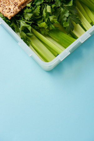 close up view of food container full of healthy parsley and celery isolated on blueの写真素材