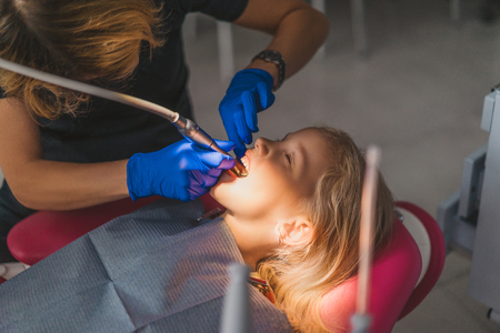 partial view of dentist in latex gloves treating little kids teeth at dentist officeの写真素材