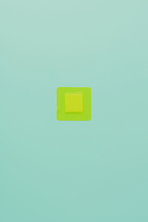 top view of green square adhesive bandage on blue