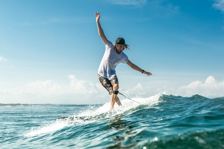 male surfer riding waves in ocean at Nusa Dua Beach, Bali, Indonesiaの写真素材