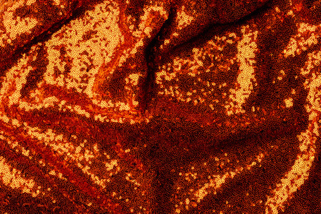 top view of dark orange textile with shiny sequins as background