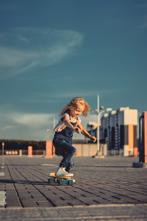 smiling little child riding on skateboard at parking lotの写真素材