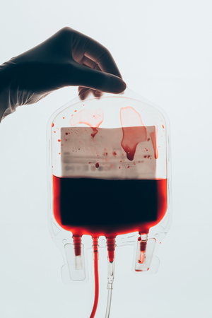 cropped shot of doctor holding plastic bag of blood for transfusion isolated on whiteの写真素材