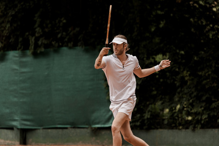 handsome retro styled man playing tennis at court