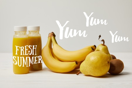 yellow detox smoothies in bottles with bananas, pears and kiwis on white background, fresh summer...