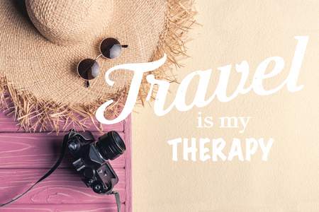 Straw hat with sunglasses and camera on light sand with "travel is my therapy" inspectionの写真素材