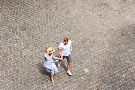 high angle view of woman in straw hat walking with redhead boyfriend at city streetの写真素材
