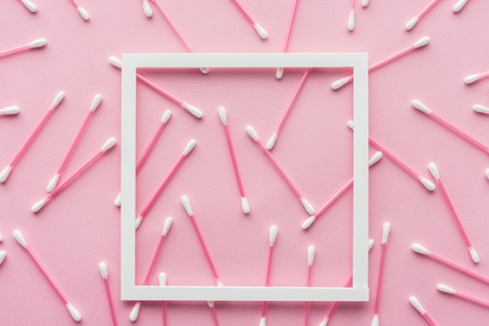top view of cotton swabs with white frame isolated on pink, beauty conceptの写真素材