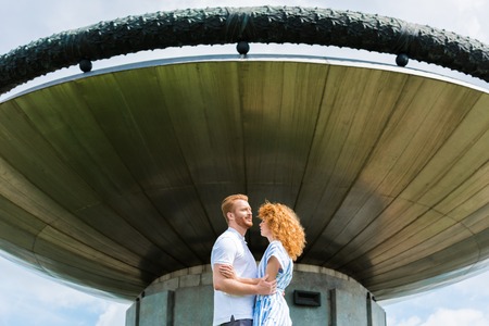 redhead couple embracing each other in front of modern buildingの写真素材