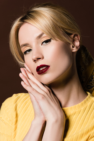 portrait of seductive blonde girl looking at camera isolated on brownの写真素材