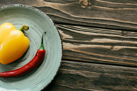 Plate with chili and bell peppers on wooden tableの写真素材