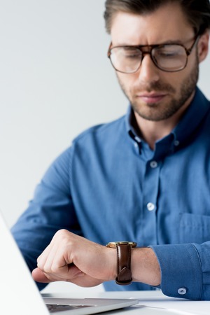 handsome young businessman looking at watch during work isolated on white