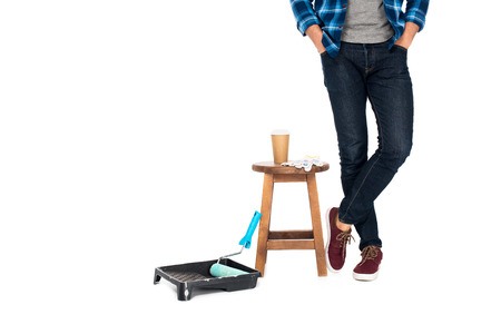 cropped shot of man standing near chair with protective gloves, coffee cup and roller tray with...