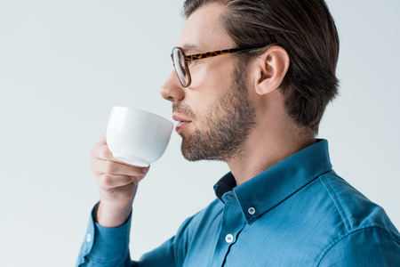 side view of young man drinking coffee from cup isolated on whiteの写真素材