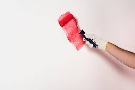 cropped shot of man painting wall in red by paint rollerの写真素材
