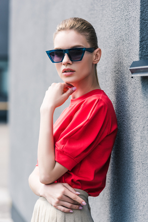 stylish young female model in sunglasses with hand on chinの写真素材