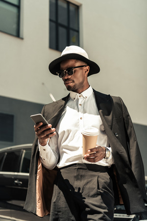 Handsome young african american businessman listening to music and holding coffee cupの写真素材