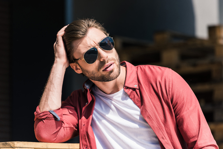 portrait of stylish young man in sunglasses holding hand on haircutの写真素材
