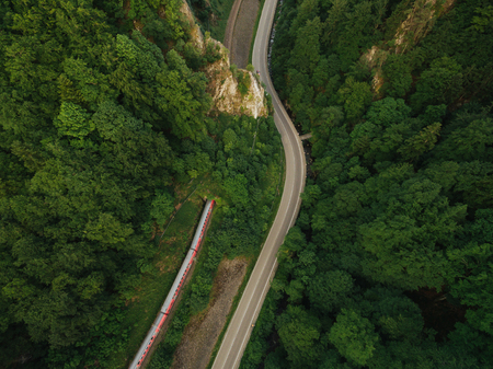 aerial view of road in beautiful mountain forest with train on railroadの写真素材