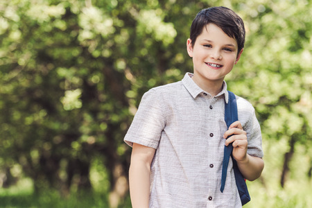 smiling schoolboy with backpack looking at camera outdoorsの写真素材