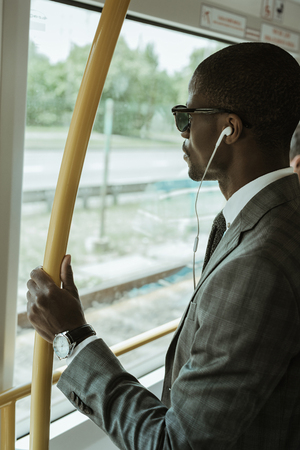African american confident businessman listening to music while going to work by trainの写真素材