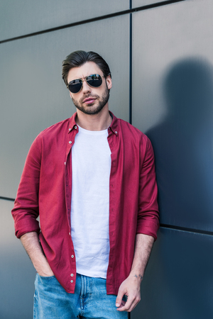 stylish young male model in sunglasses posing near black wallの写真素材