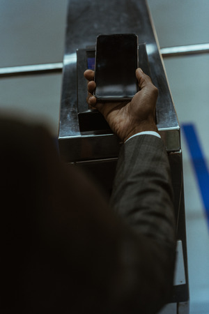 Cropped view of male hand with smartphone paying for public transport ticketの写真素材