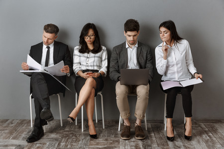 multiethnic business people with digital devices and folders waiting for job interviewの写真素材