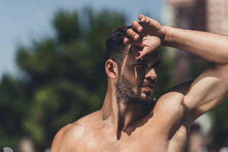 close-up portrait of shirtless young man standing on race track after workout and wiping foreheadの写真素材