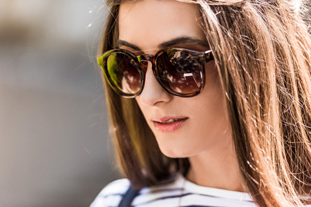 portrait of of beautiful young woman in sunglasses on streetの写真素材