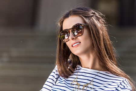 portrait of of beautiful young woman in sunglasses on streetの写真素材