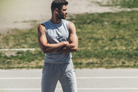 muscular young man with crossed arms on running trackの写真素材