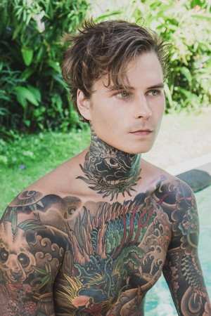 portrait of pensive tattooed young man looking away, bali, indonesiaの写真素材