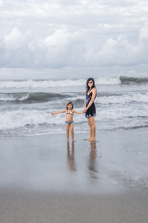 mother and daughter spending time on seashore together on cloudy dayの写真素材