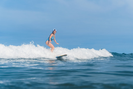 woman in swimming suit surfing in oceanの写真素材
